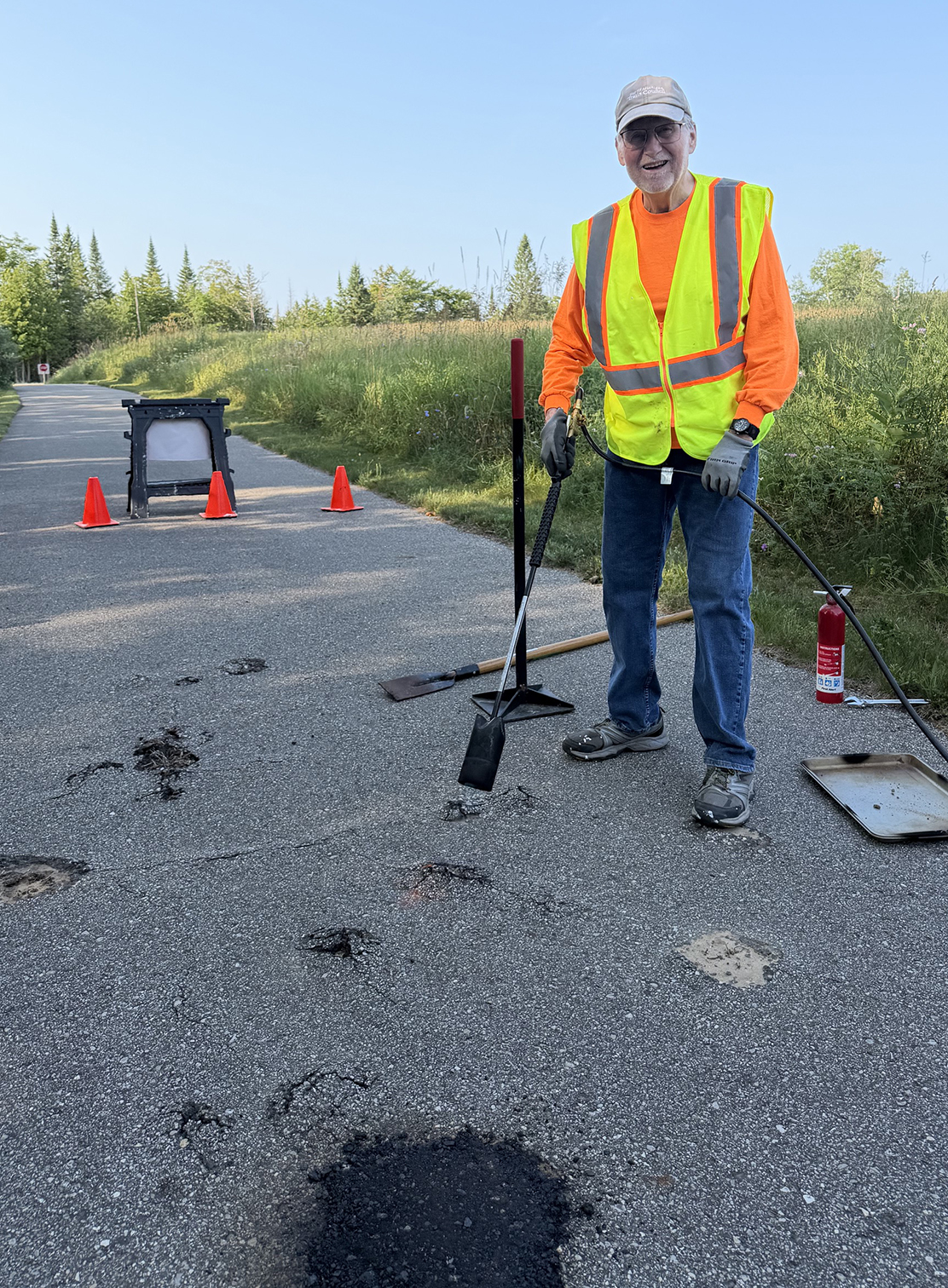 Safety & Maintenance Director Bill Prall grinding down a root bump on a paved trail
