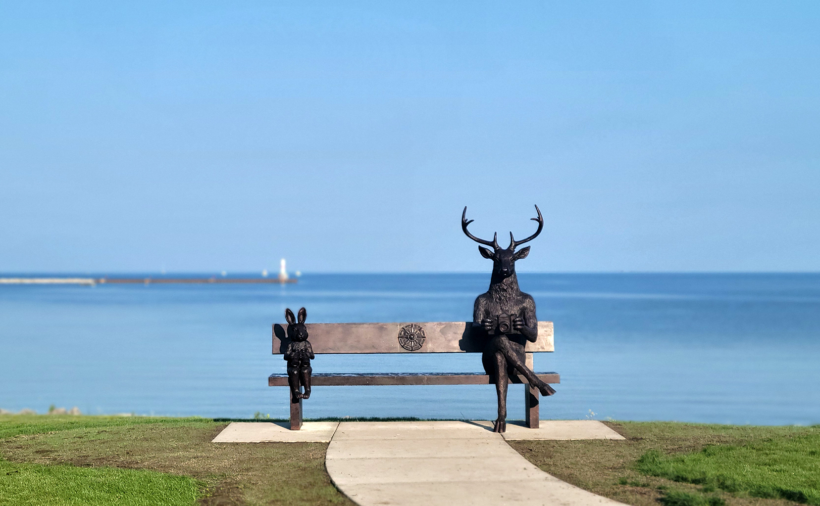 Bronze deer and rabbit sculpture on a park bench at Bayfront Park in Petoskey
